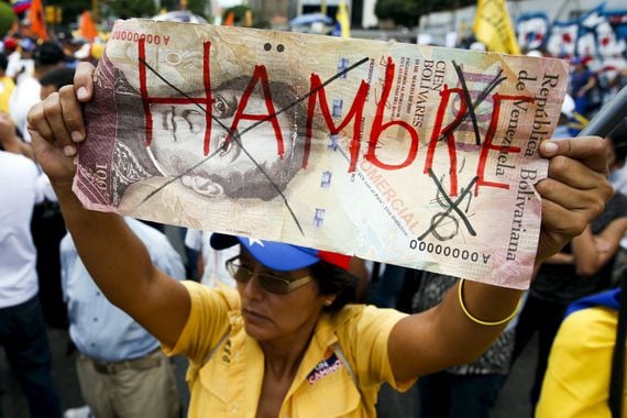 opposition-supporter-holds-up-a-giant-hundred-bolivares-note-with-the-word-hungry-written-on-it-during-a-gathering-to-protest-against-the-government-of-venezuelas-president-nicolas-maduro-and