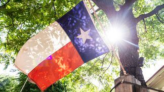 sun-shining-through-tree-backlighting-lone-star-state-flag-in-austin-texas-usa