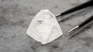 raw-diamond-big-dob-on-concrete-surface-next-to-tweezers